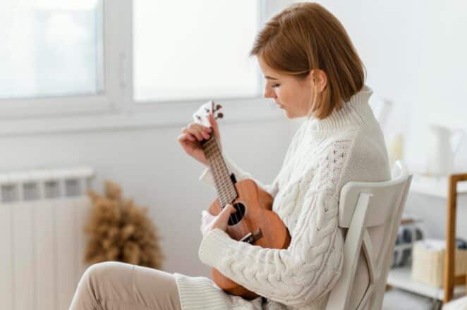 Mulher tocando ukulele com foco na expressão tranquila, em um ambiente iluminado. A imagem transmite uma sensação de serenidade, que pode ser associada ao momento de reflexão e escuta de músicas de luto.